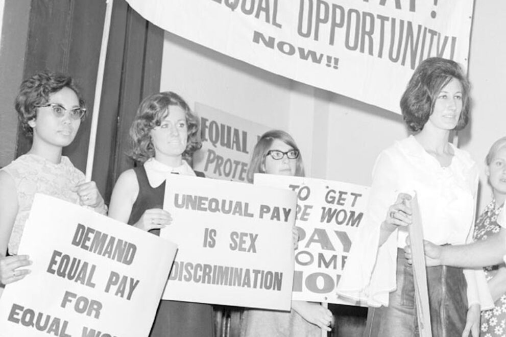 A photo from 1969 of a group of women outside Victorian parliament holding signs about equal pay.